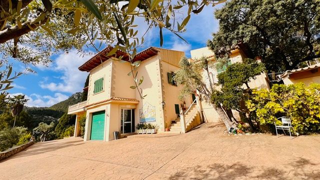 Two-story Mediterranean home with turquoise accents and stairs leading to upper level.