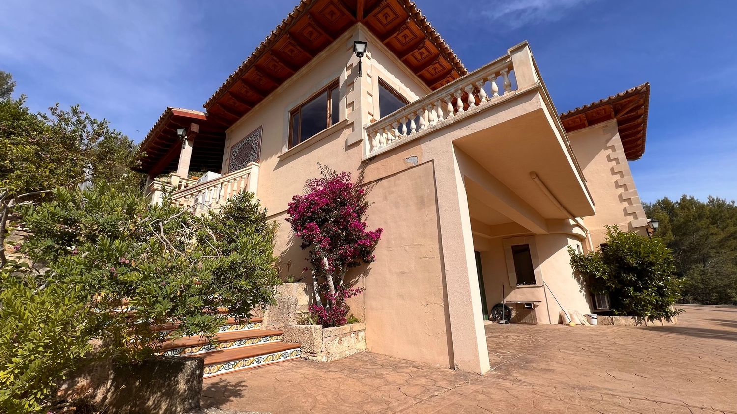 Elegant Mediterranean villa with pink facade, terracotta roof, and ornate architectural details.