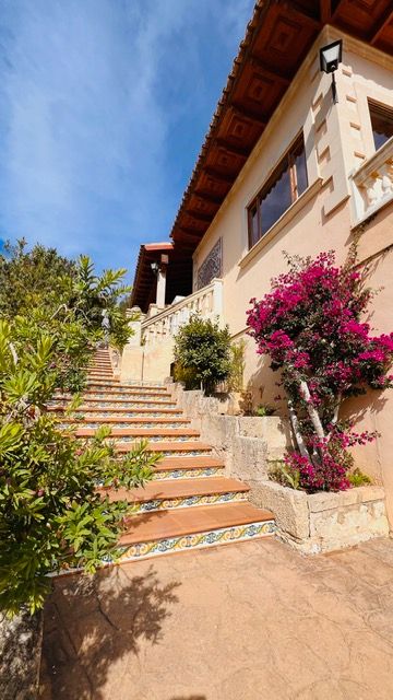 Decorative tiled steps leading to Mediterranean villa entrance adorned with bright bougainvillea flowers.