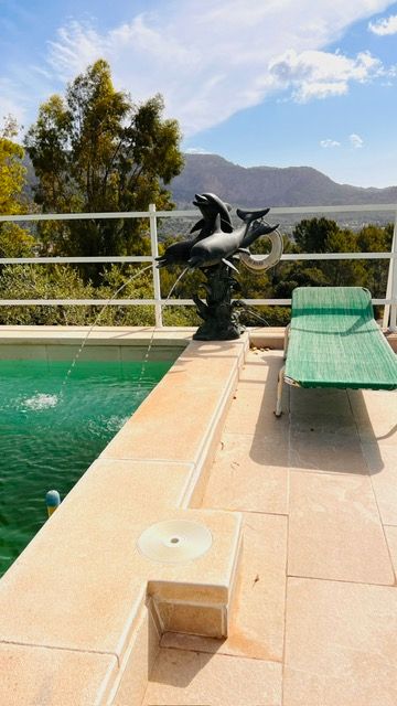 Swimming pool deck with mountain views featuring a decorative crane fountain sculpture and lounge chair.