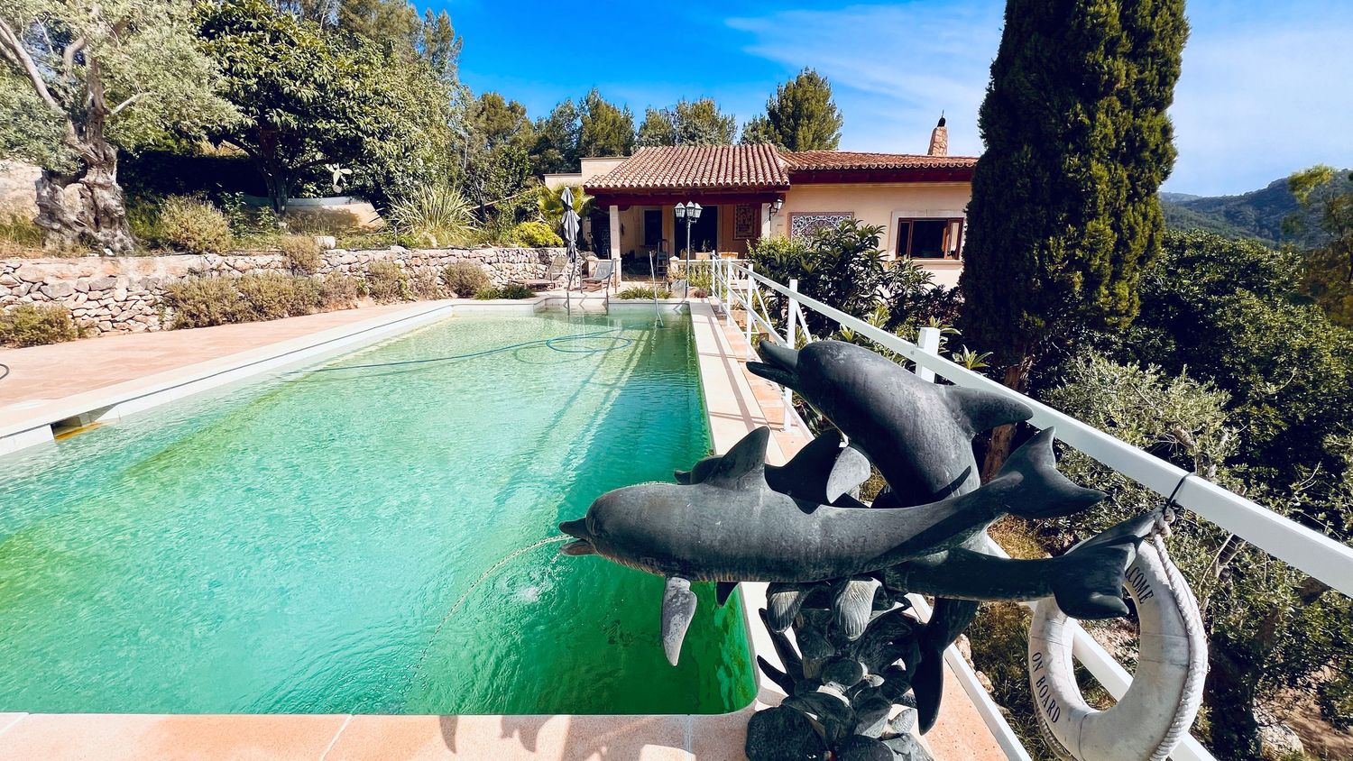 A swimming pool with mountain views features a decorative motorcycle sculpture along its edge.