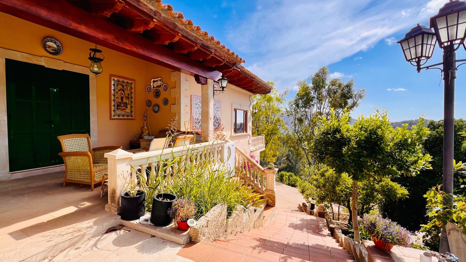 Spanish villa terrace with comfortable seating, potted plants, and mountain views.