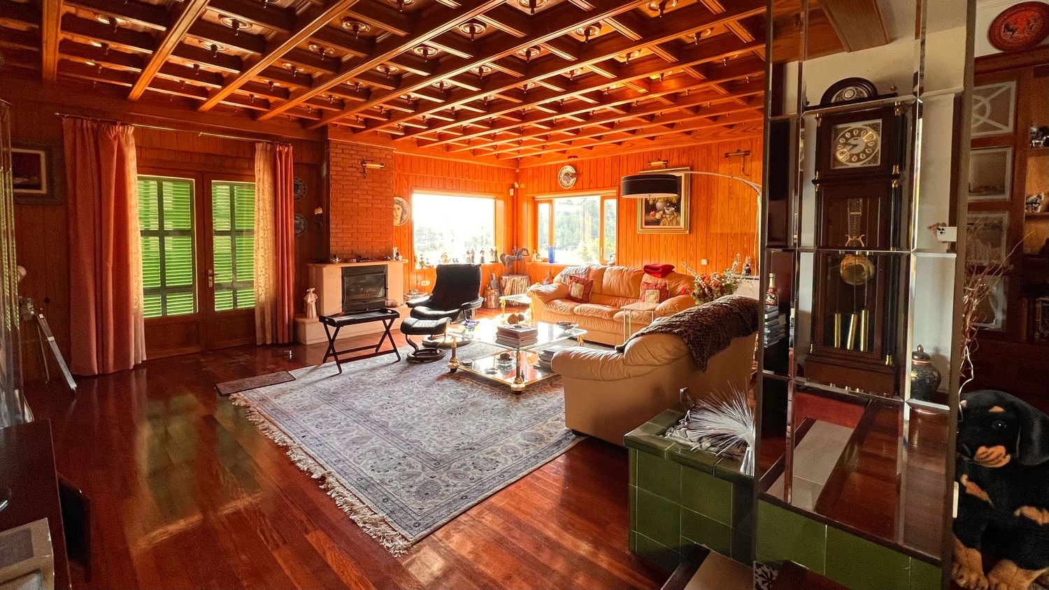 Spacious living room with wooden coffered ceiling, orange walls, and comfortable seating arrangement.