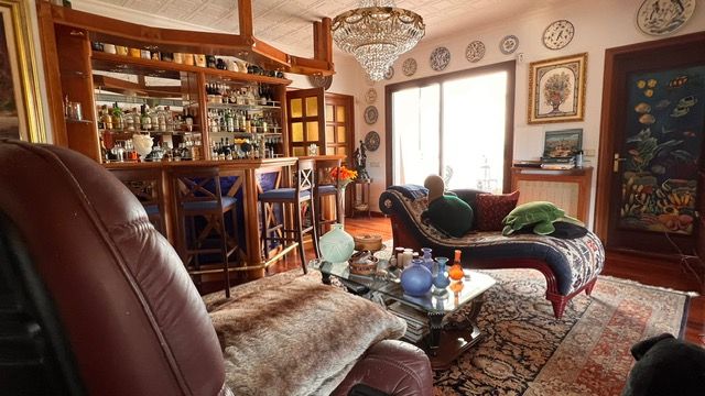 Luxurious living room with home bar, crystal chandelier, and cozy leather seating.
