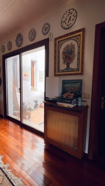 Hallway with sliding glass doors, decorative plates, and framed artwork on white walls.