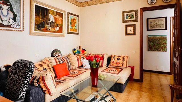 Modern living space with ethnic-inspired decor featuring orange accents and a glass coffee table.