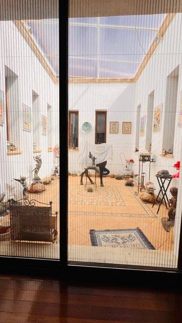 Bright indoor gallery space with sculptures and artwork viewed through glass doors.