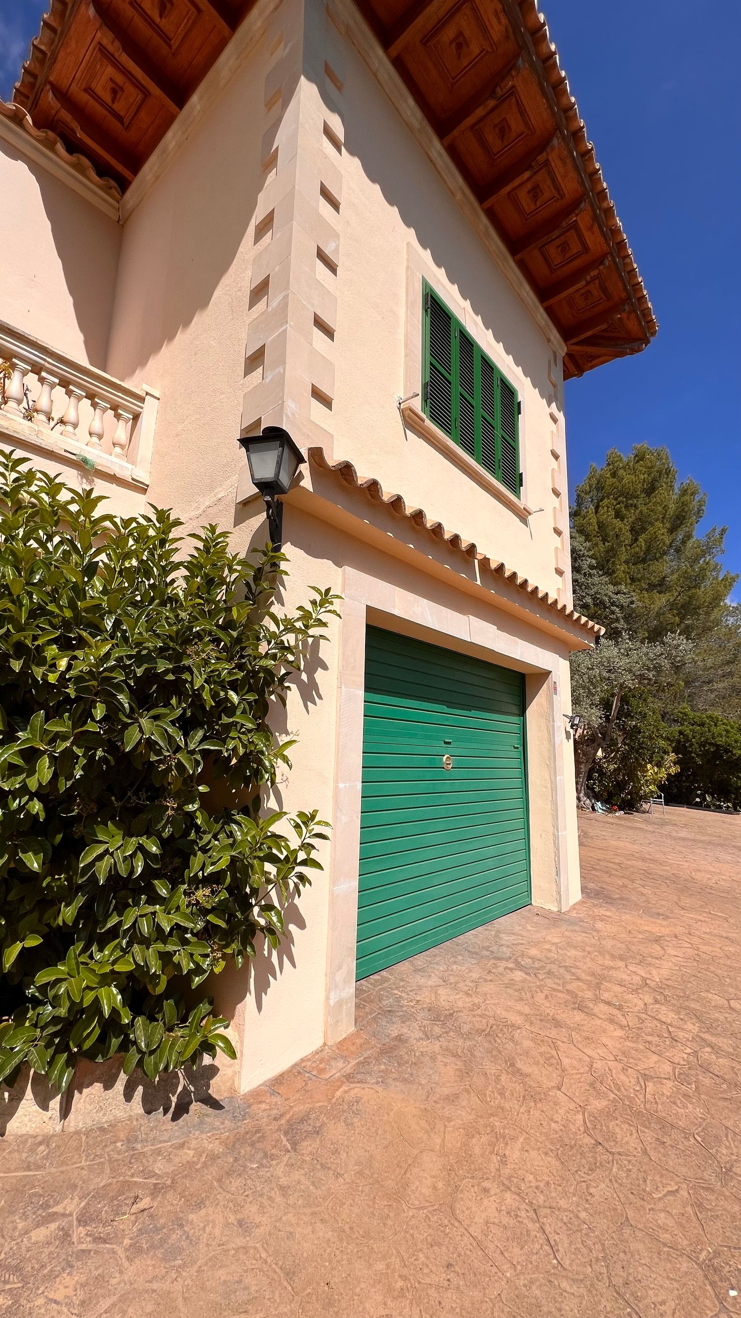 Mediterranean style house exterior with green garage door and decorative stone corner details.