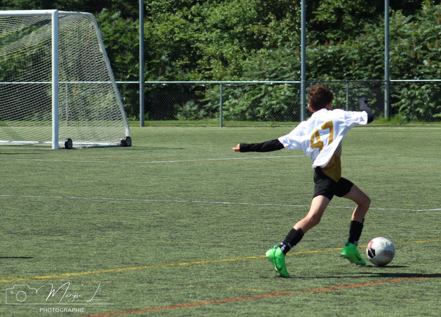 Soccer player in white uniform prepares to kick ball on green sports field.