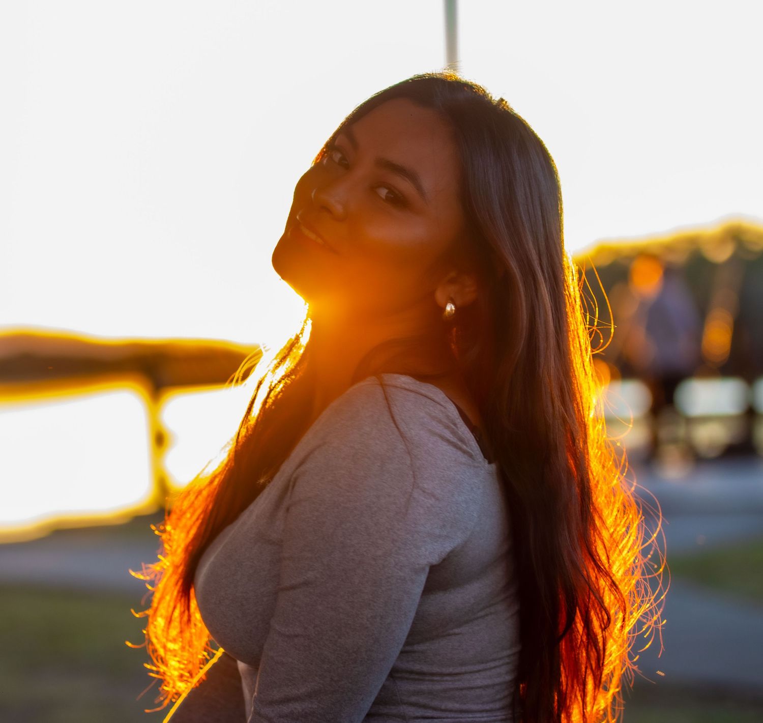 Golden hour portrait with long hair glowing in sunset light.