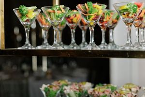 Colorful fresh salads served in martini glasses on a tiered display at a catered event.