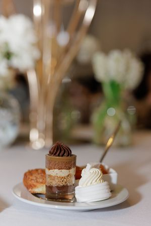 Elegant dessert plate with layered chocolate mousse cup, meringue, and pastry at a wedding reception.