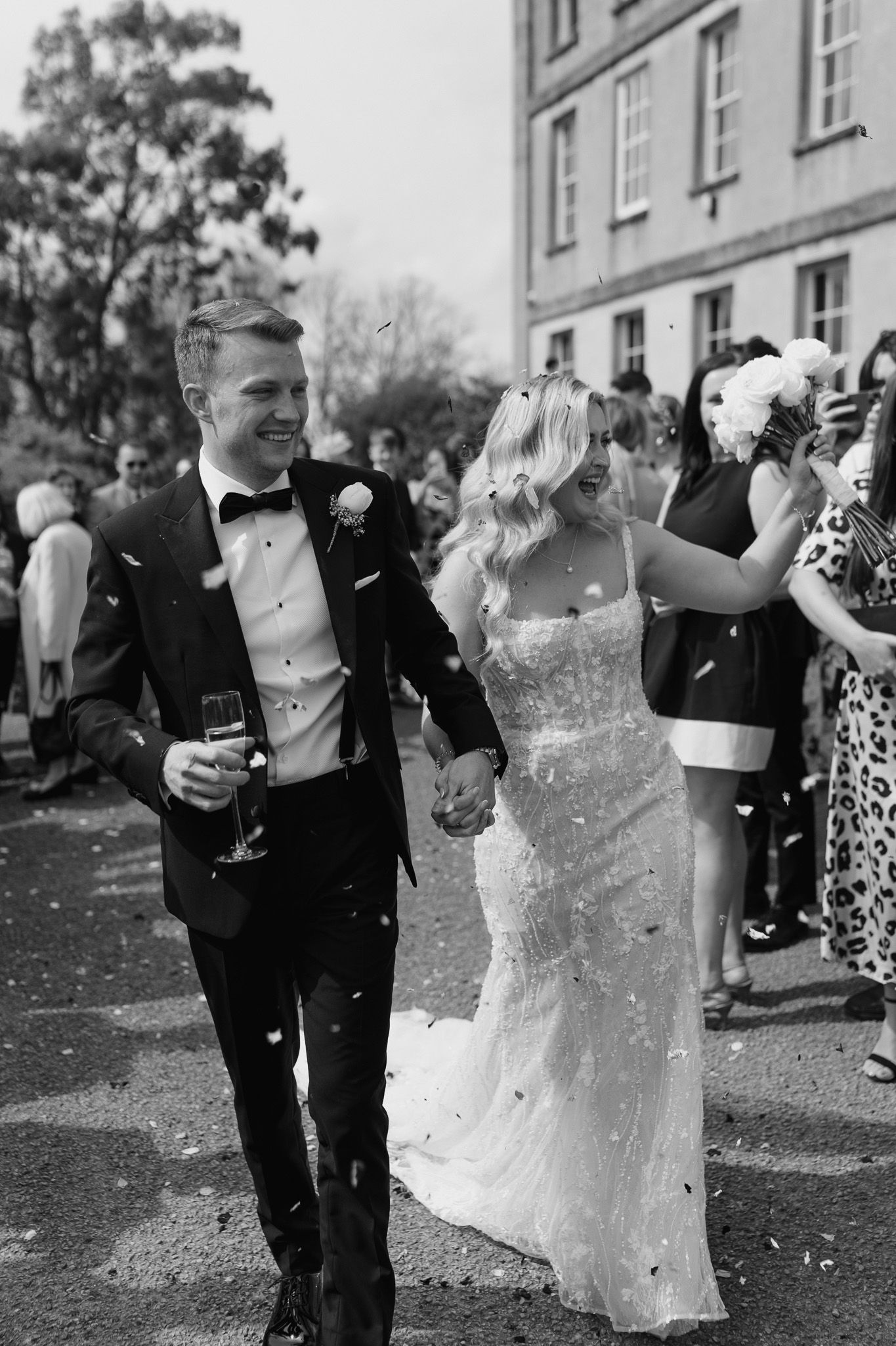 A candid black and white photo of newlyweds celebrating outdoors.
