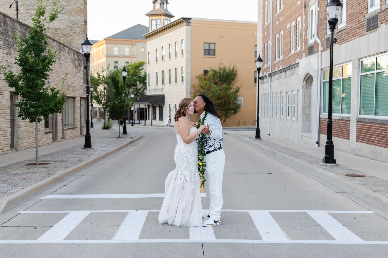 Bride and groom kissing in sidewalk on a city street with an urban feel.