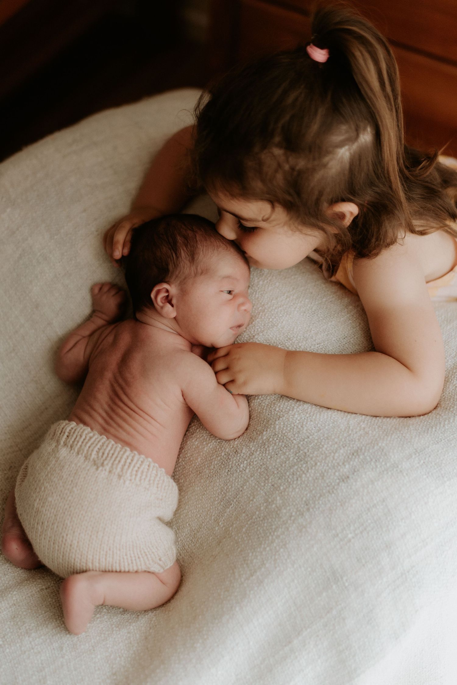 A natural professional family photo of a newborn baby and her toddler sister at home