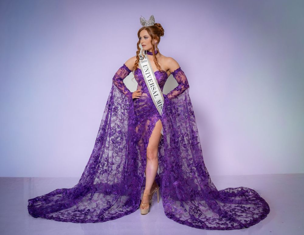Woman in purple lace gown and crown wearing a pageant sash poses elegantly for a beauty competition photo.
