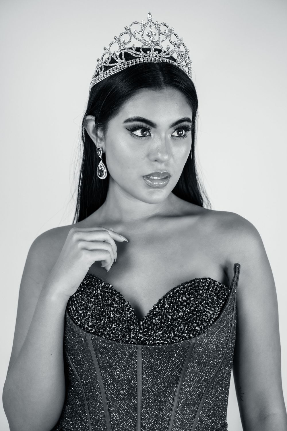 Pageant contestant wearing sparkly black gown and ornate tiara in black and white portrait.