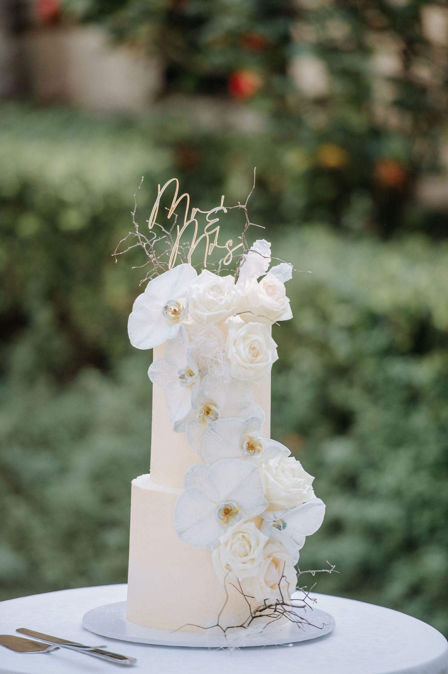 Elegant white wedding cake decorated with fresh roses and gold wire accents.