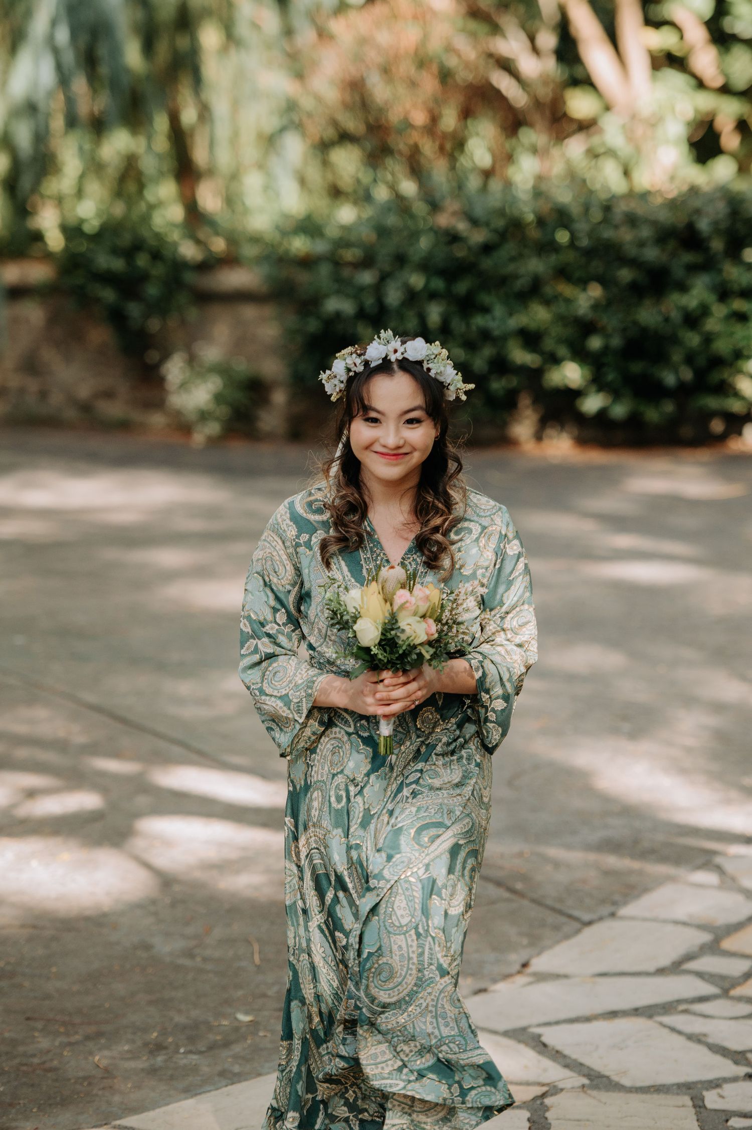 A person in floral robe holding yellow bouquet during wedding preparations.