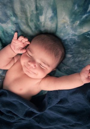Peaceful sleeping newborn on soft blue textured blanket.