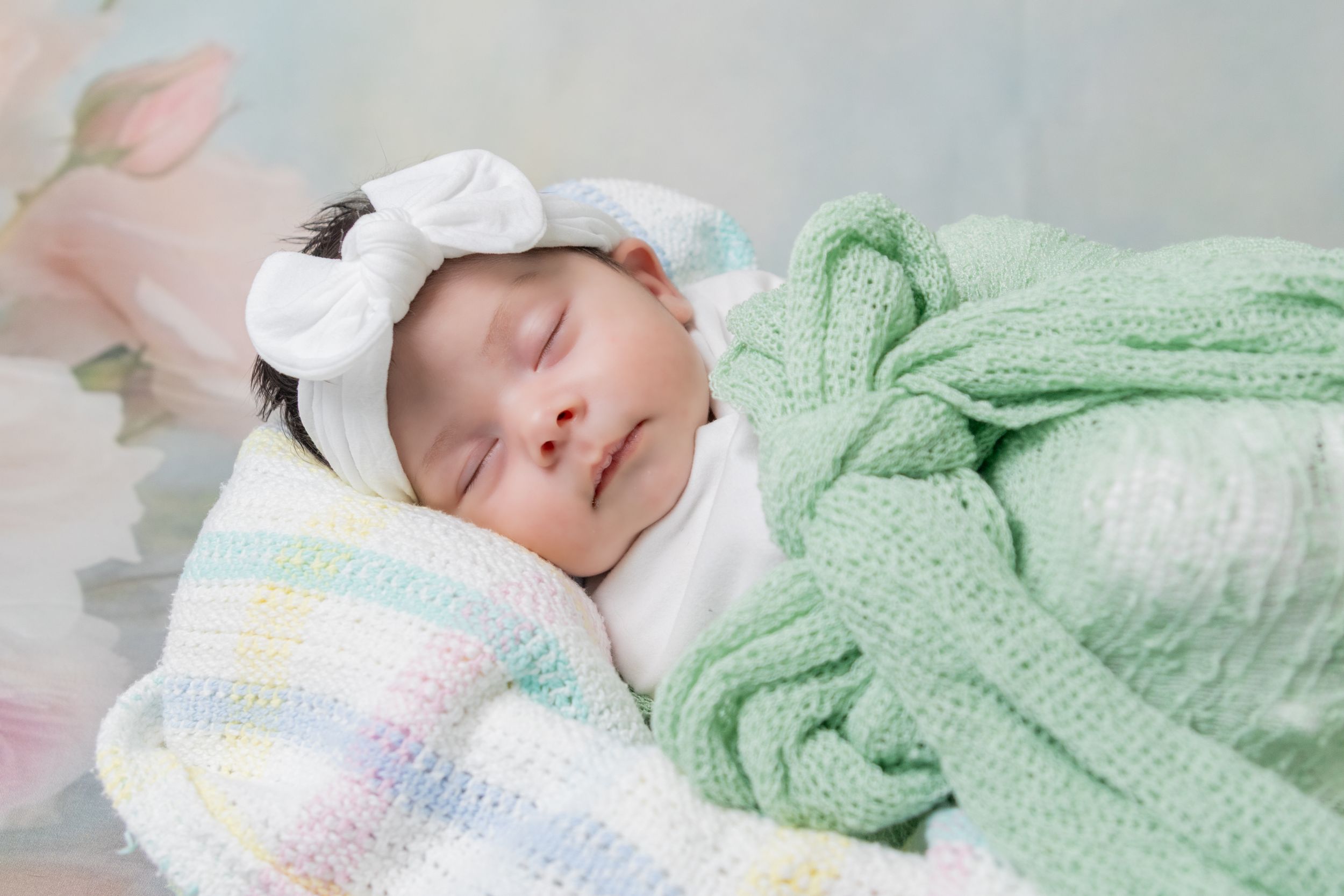 Peaceful baby sleeping under mint green blanket.