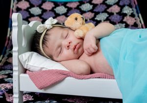 Sleeping infant on pink pillow with floral background.