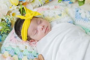 Sleeping baby on floral bedding with yellow flower accents.