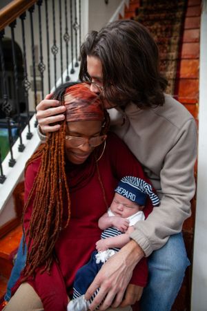 Family sharing tender moment together on carpeted stairs indoors.