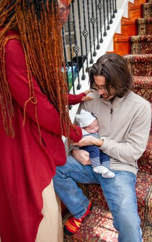 Intimate family scene with red sweater and jeans on patterned carpet by stairs.