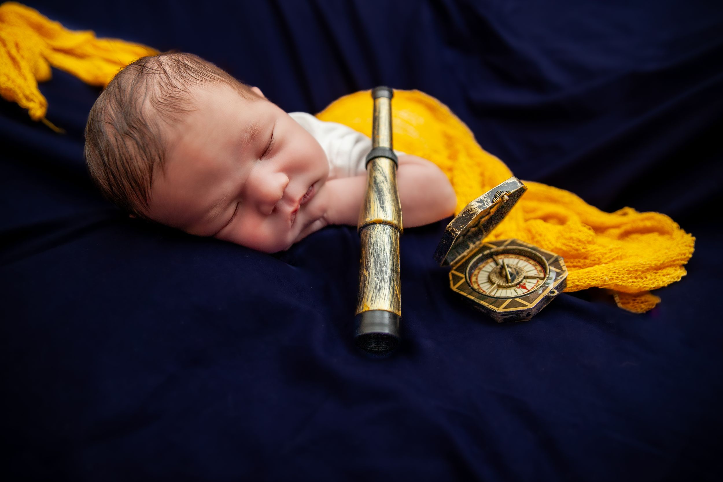 Sleeping infant on navy blue blanket with gold accent fabric.