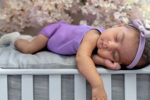 Person sleeping peacefully on a white wooden fence outdoors.