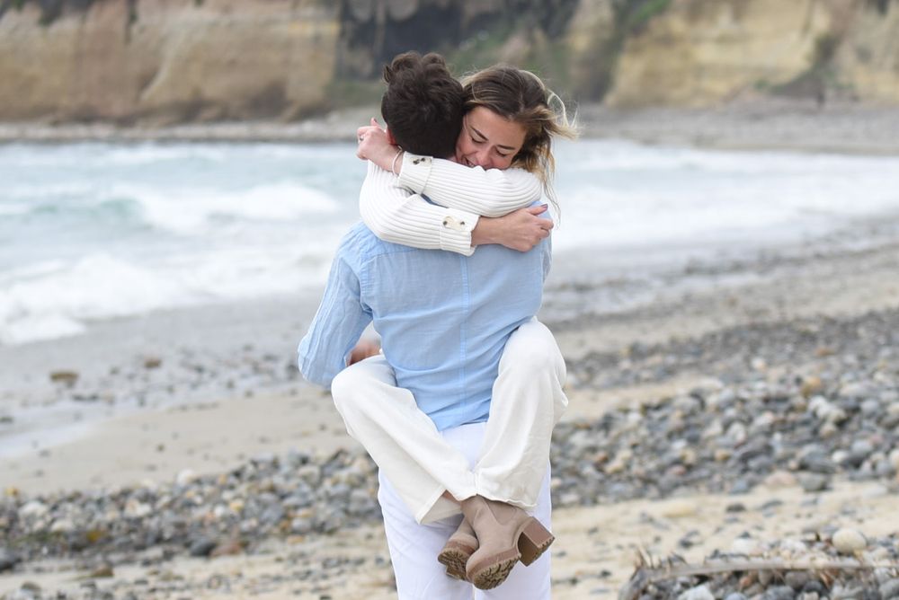 A romantic lift on a rocky beach with coastal cliffs in the background.