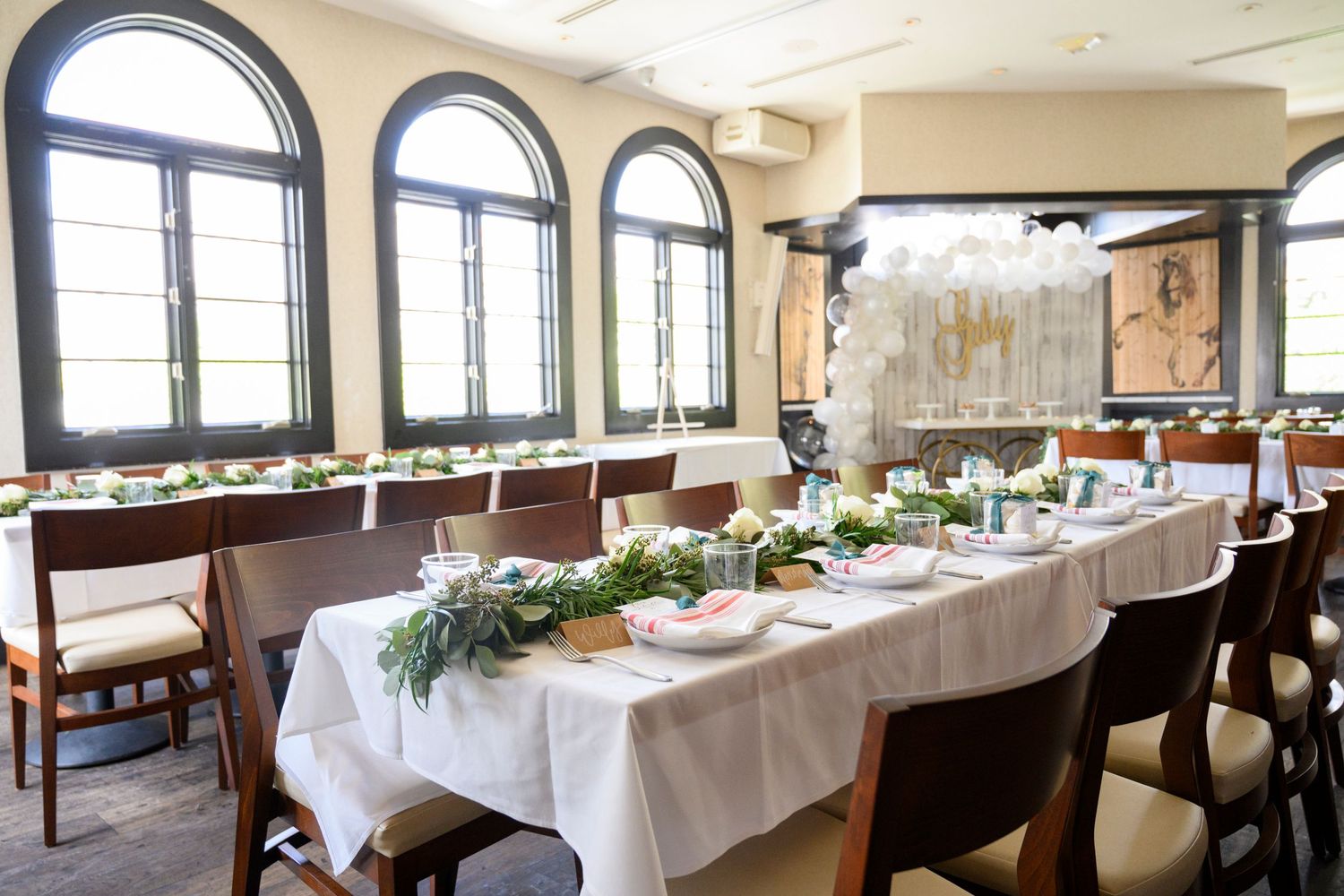 Elegant dining room with arched windows and long table set for formal occasion.