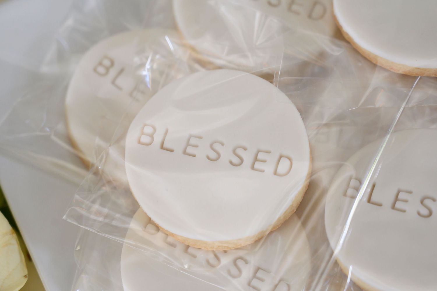 White cookies with the word 'BLESSED' imprinted on them wrapped in clear packaging.