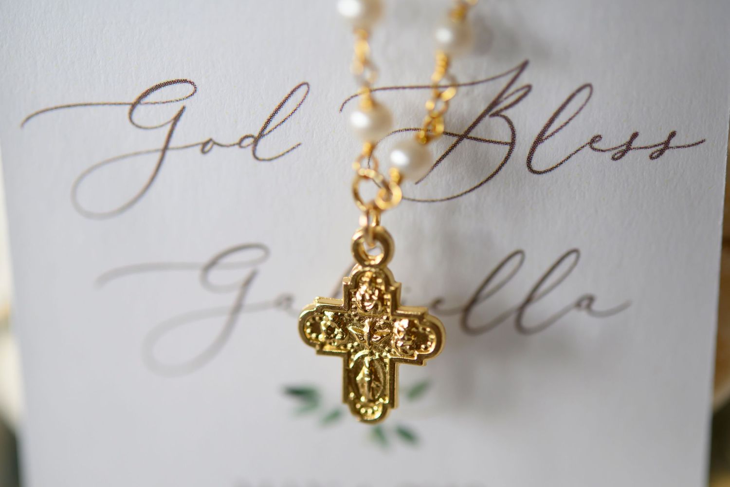 Gold cross necklace pendant displayed on elegant calligraphy card.