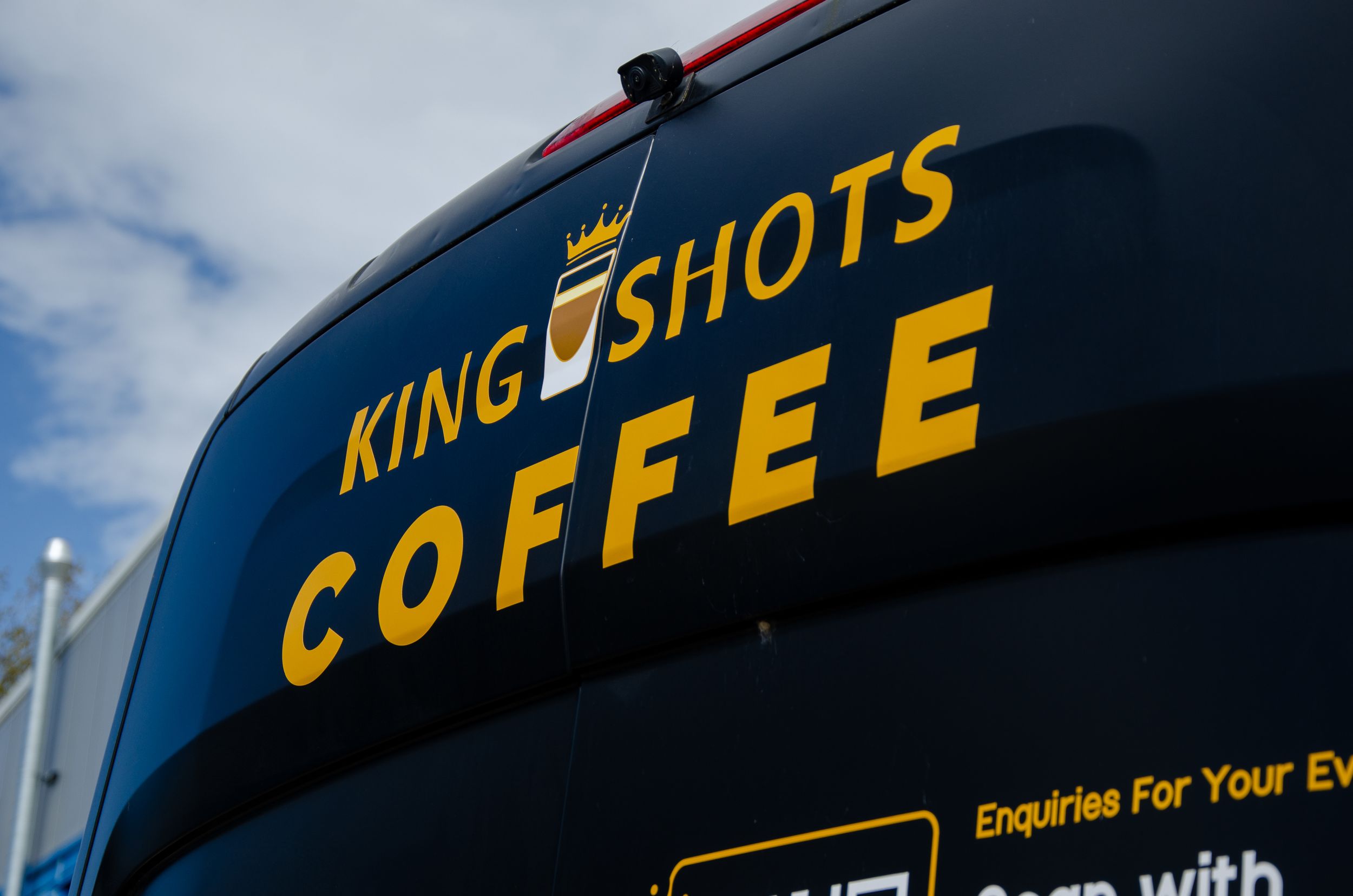 Close-up of King Shots Coffee signage in yellow text against dark blue background.