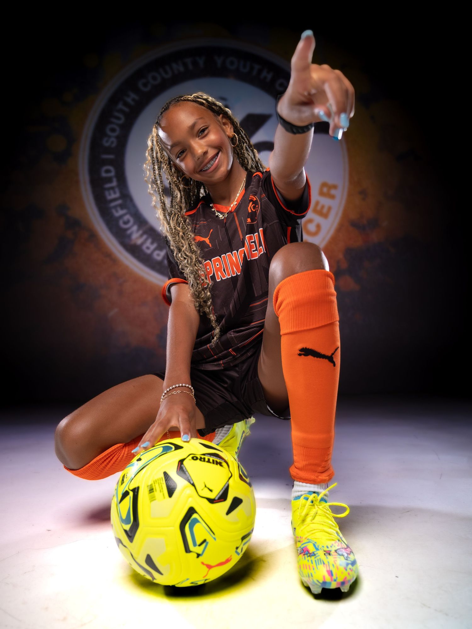 Young female soccer player poses with yellow ball in Springfield South County Youth uniform.