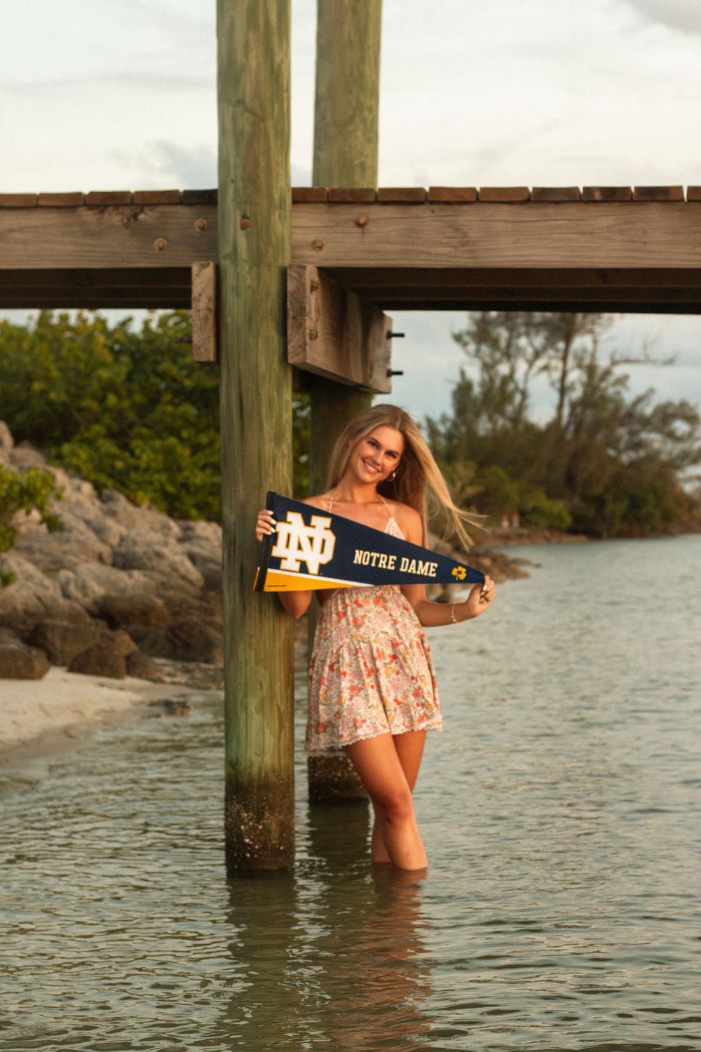 Girl holds pennant flag in the water during a senior session in Stuart, Florida