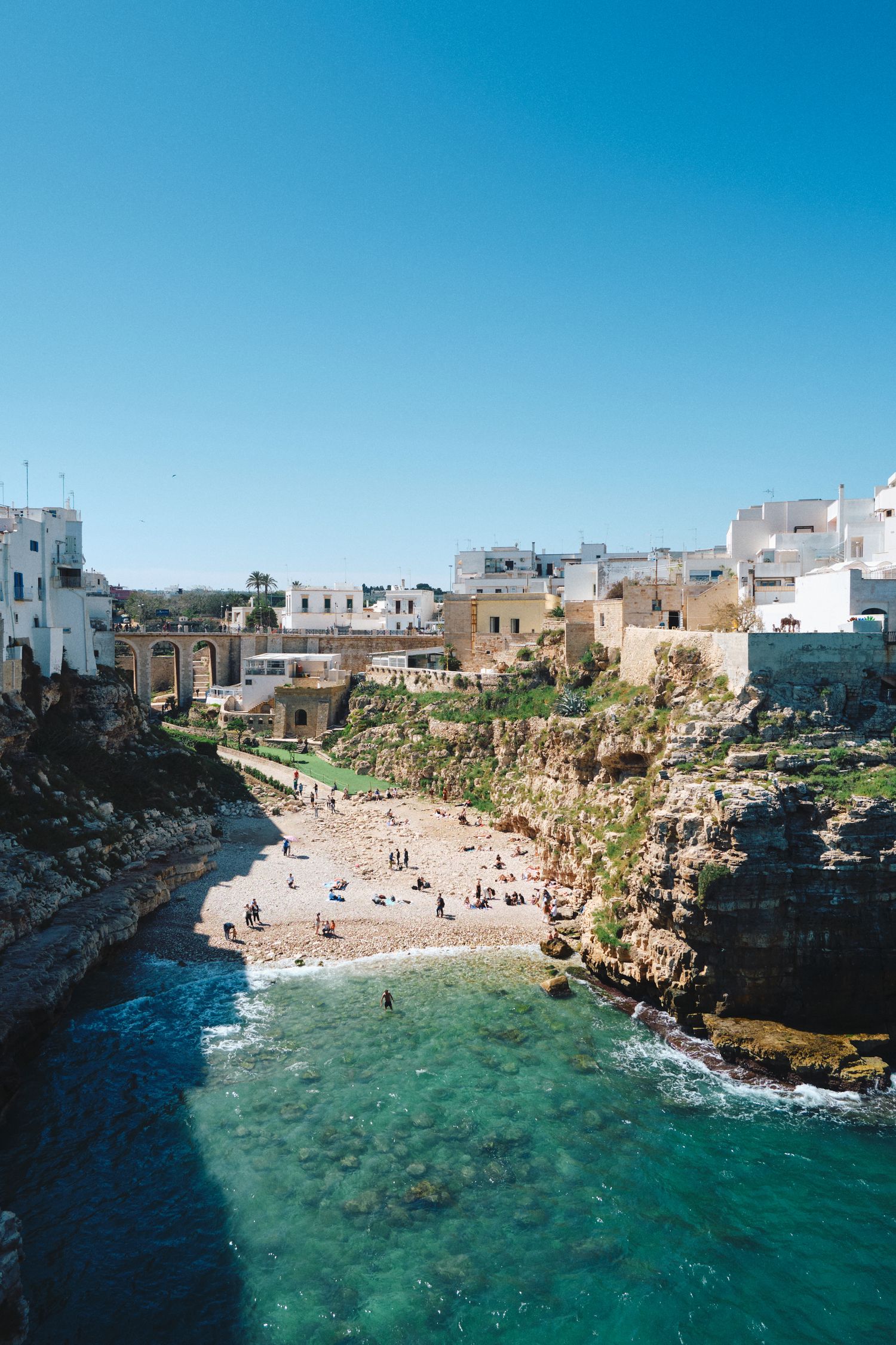 Aerial view of a secluded beach cove surrounded by white buildings and limestone cliffs.