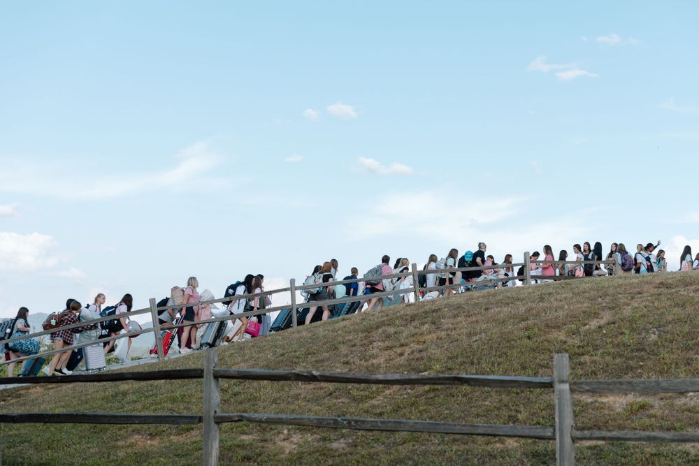 Large crowd gathered on a grassy hillside overlooking an outdoor event.