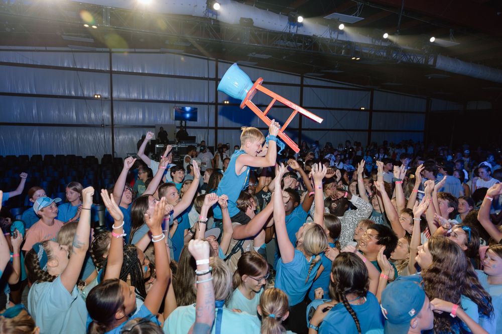 Excited crowd at a concert lifting a chair above their heads during celebration.