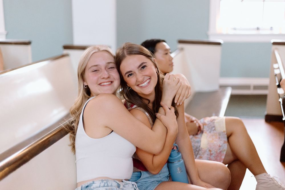 Friends share a joyful moment together while sitting in church pews.