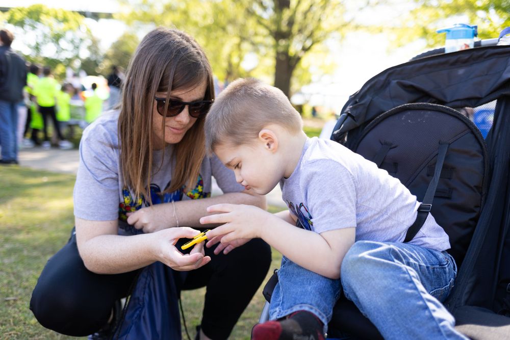 Two people examining something closely while sitting on grass outdoors.