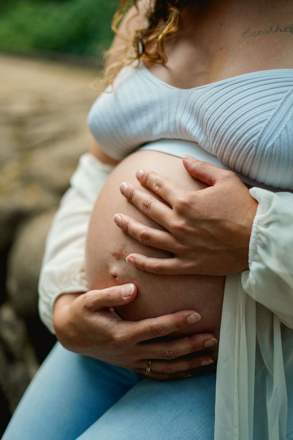 Close-up shot of hands cradling pregnant belly in soft natural lighting.