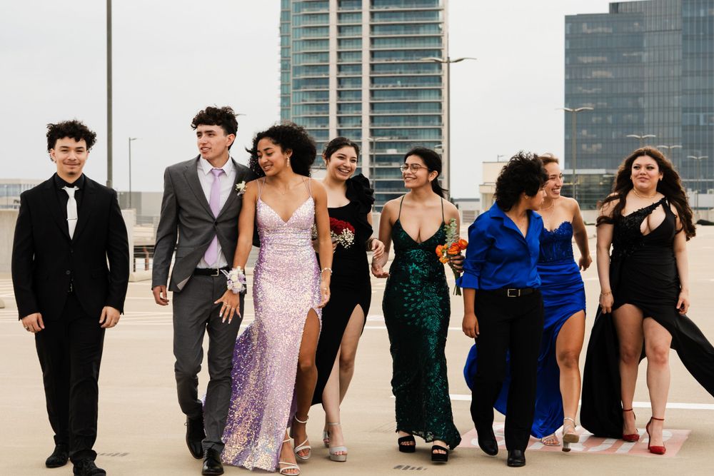 Friends walking together in formal attire on rooftop with cityscape backdrop.