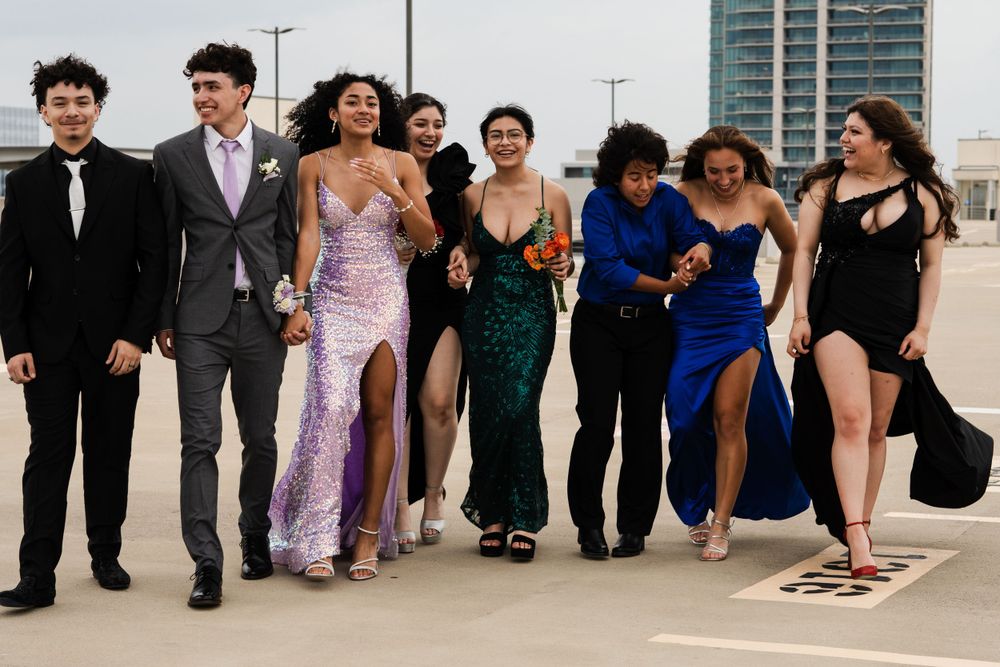 Group striking casual poses in formal wear during rooftop photoshoot.