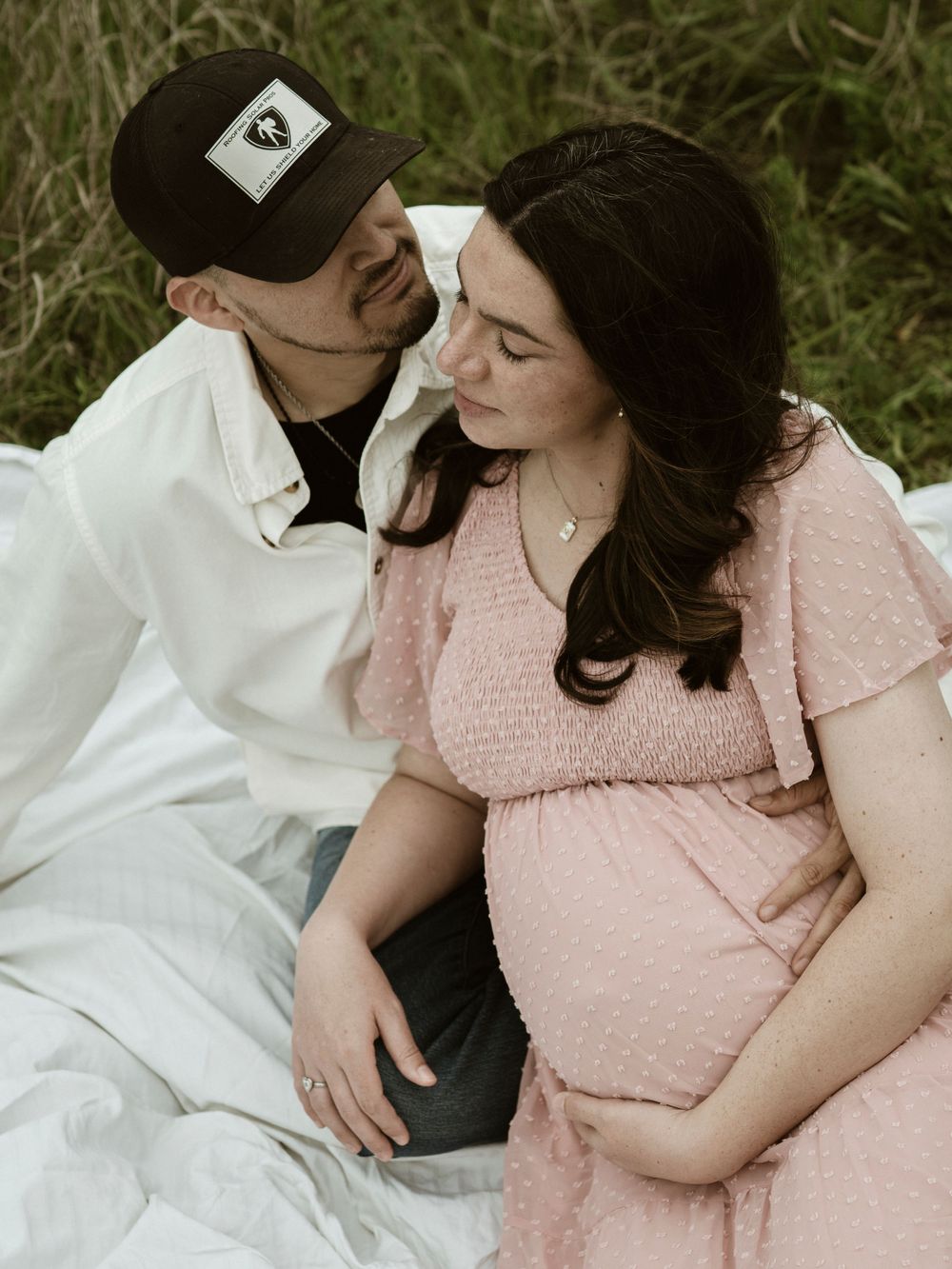 An intimate maternity portrait of an expectant couple sharing a romantic moment outdoors.