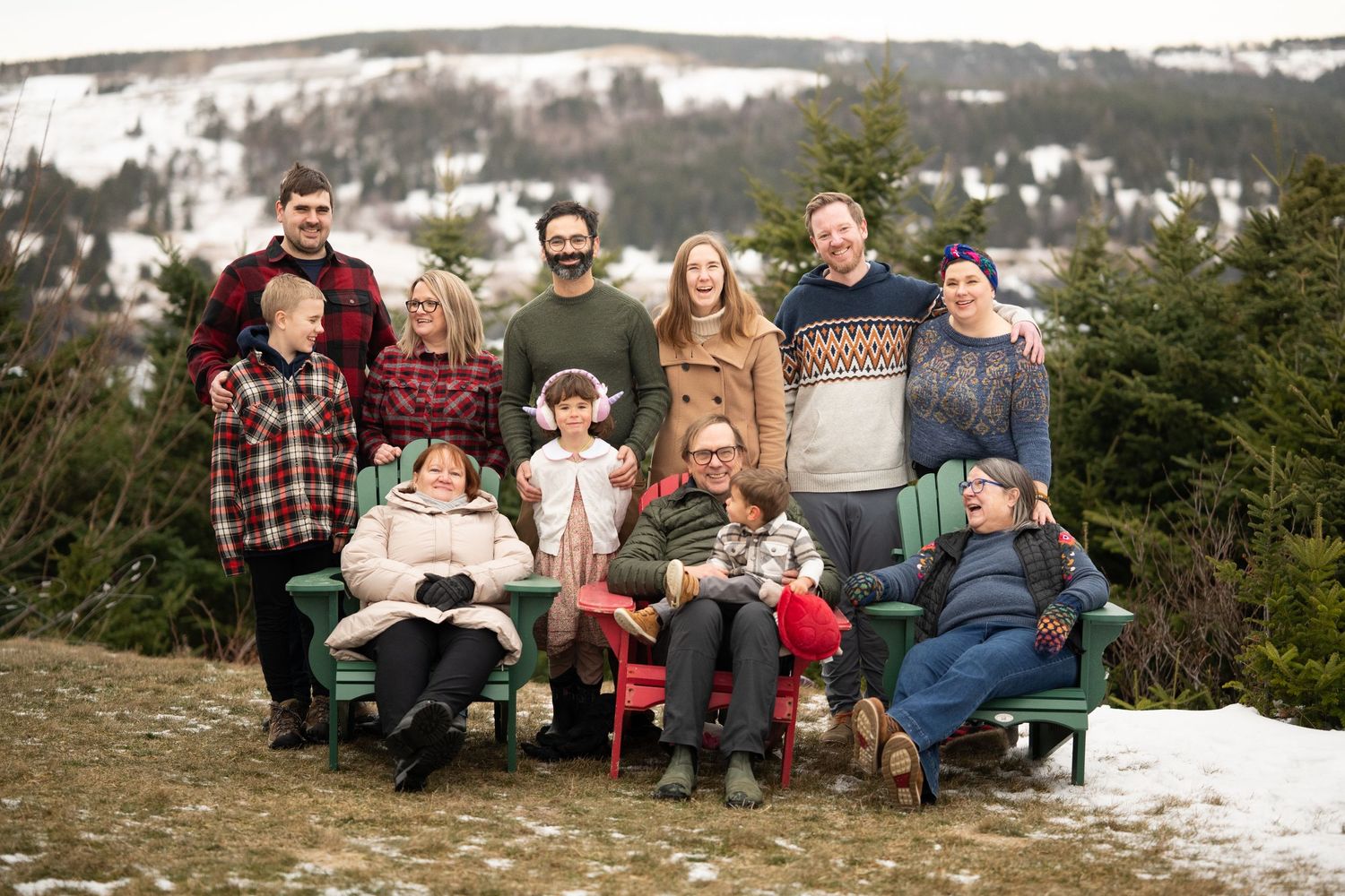 Family portrait at Middle Cove Beach, Newfoundland, wearing cozy sweaters with snow-covered hills in the background.