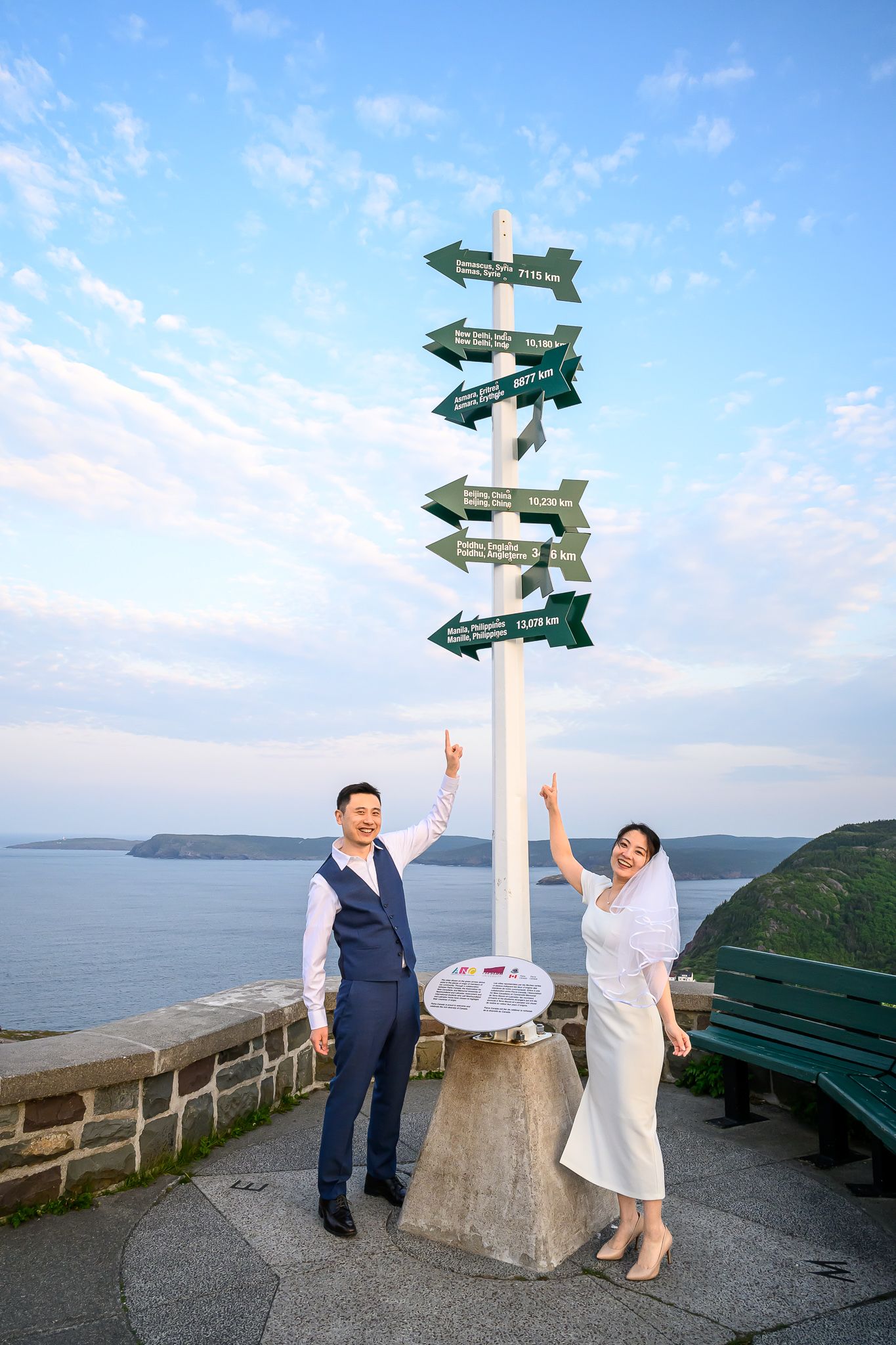 Newlywed Asian couple at the distance marker sign on top of Signal Hill, St. John's, Newfoundland.