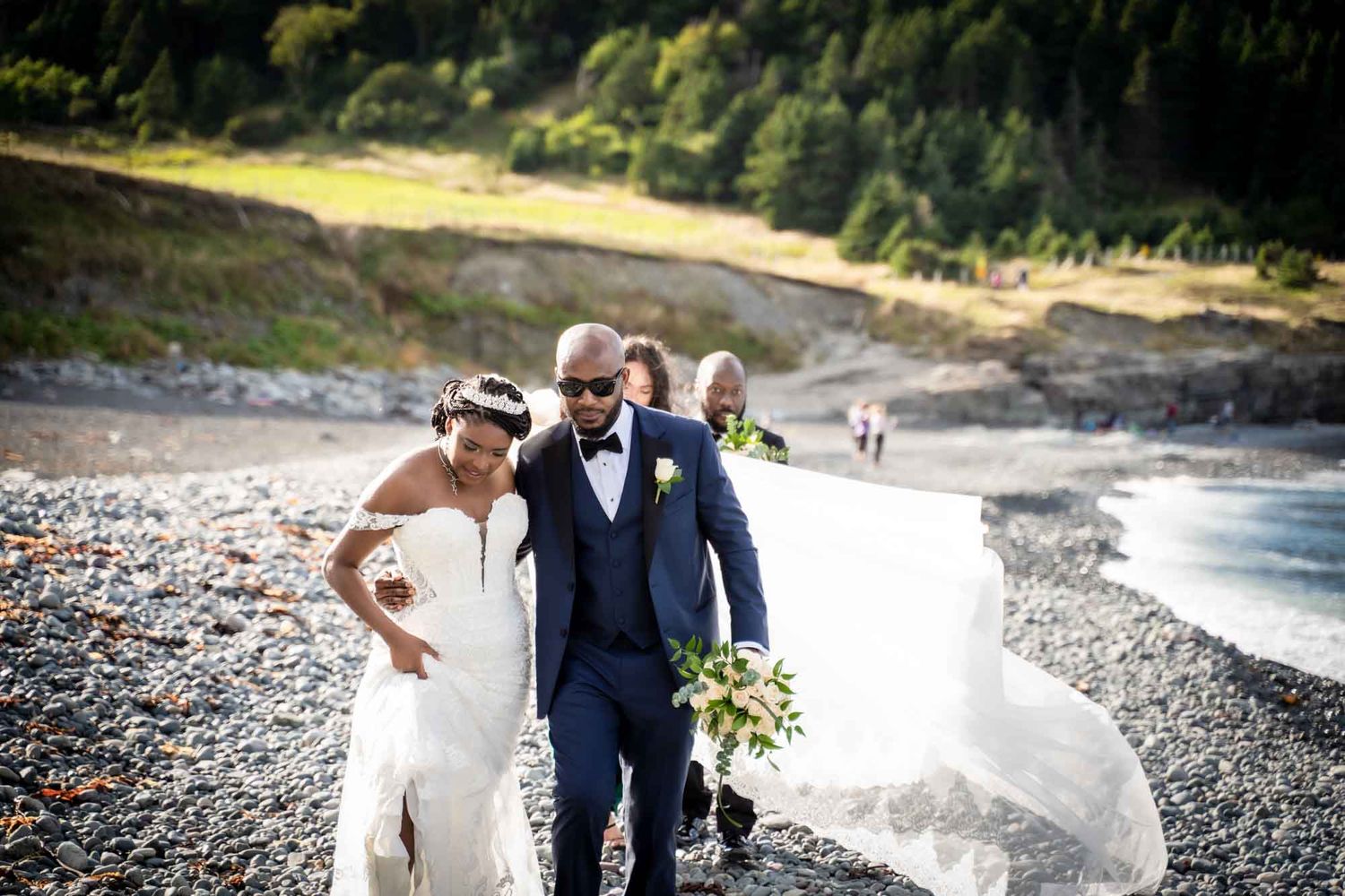 Newlywed couple walking along the rocky shoreline at Middle Cove Beach, Newfoundland.